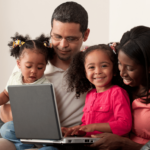 A South African family working together on a laptop to budget their expenses, focusing on how to save money on a tight budget with effective financial planning.