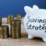 Cochinito blanco con la inscripción "Saving Strategy" rodeado de pilas de monedas, simbolizando estrategias de ahorro efectivas sobre una superficie de madera.